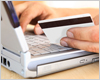 Close-up of hand leaning on keyboard, holding debit card