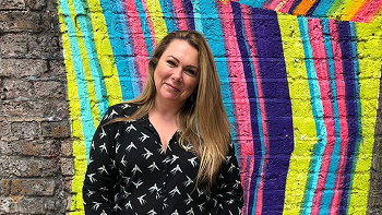 Woman smiling in front of a colorful wall
