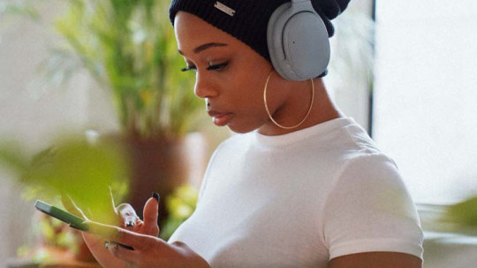 Woman using her mobile phone and wearing headphones